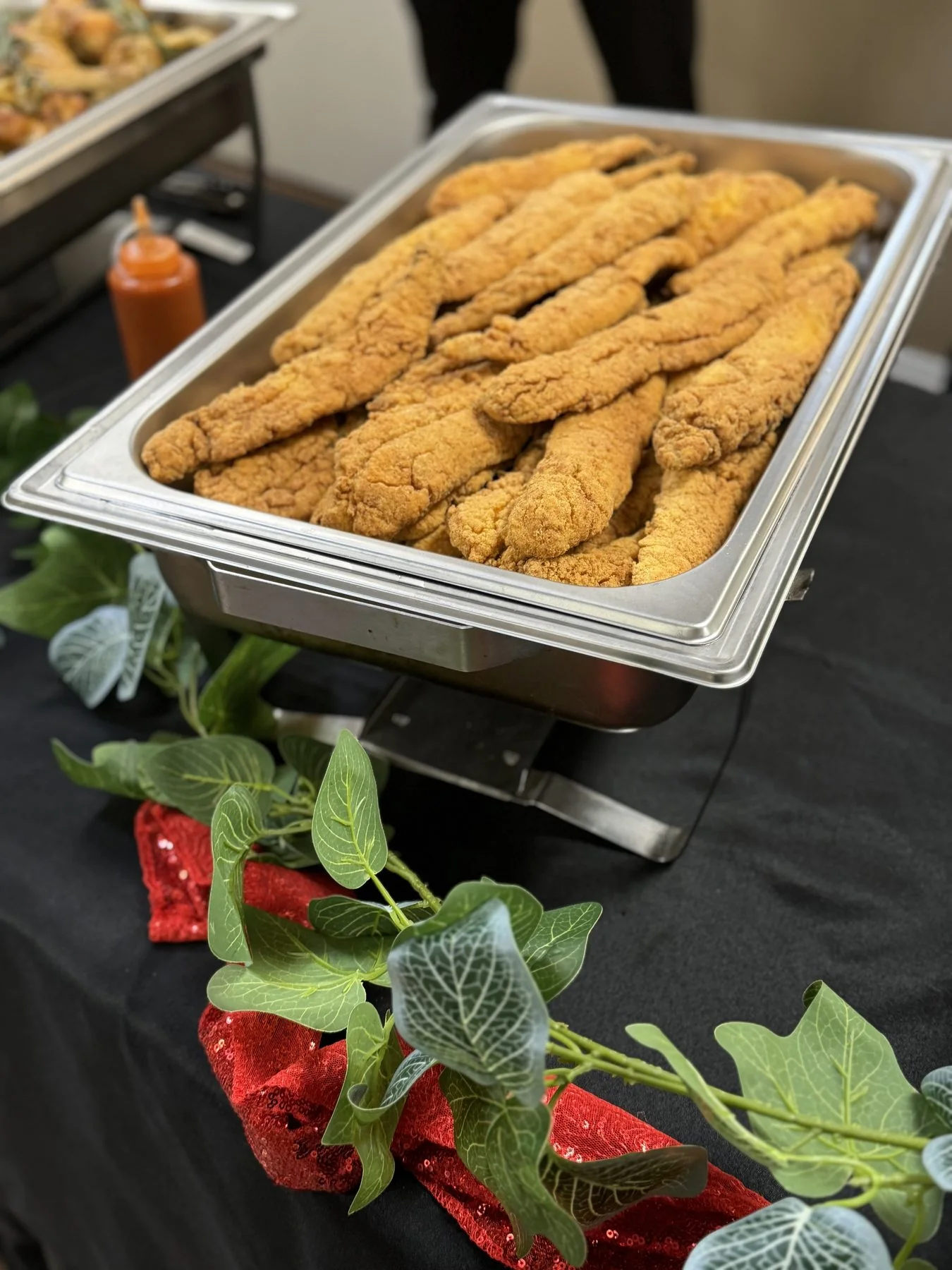 Golden fried whiting in a chafing dish on black linen with eucalyptus
