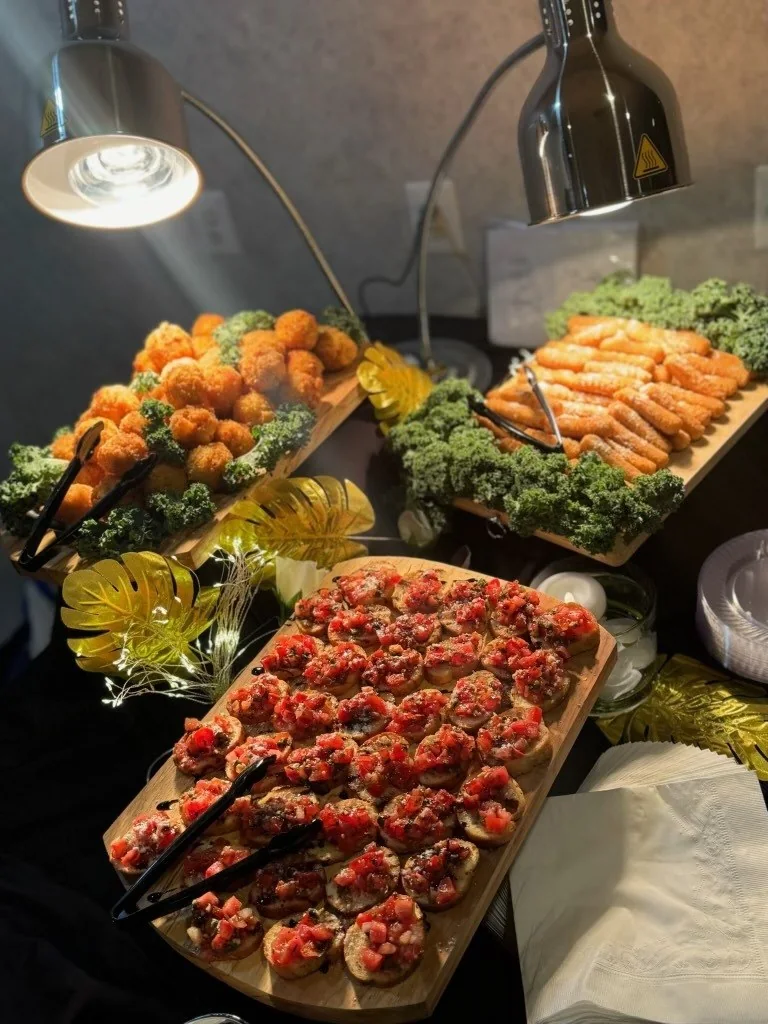 A polished corporate catering display with composed appetizers and warm dishes
