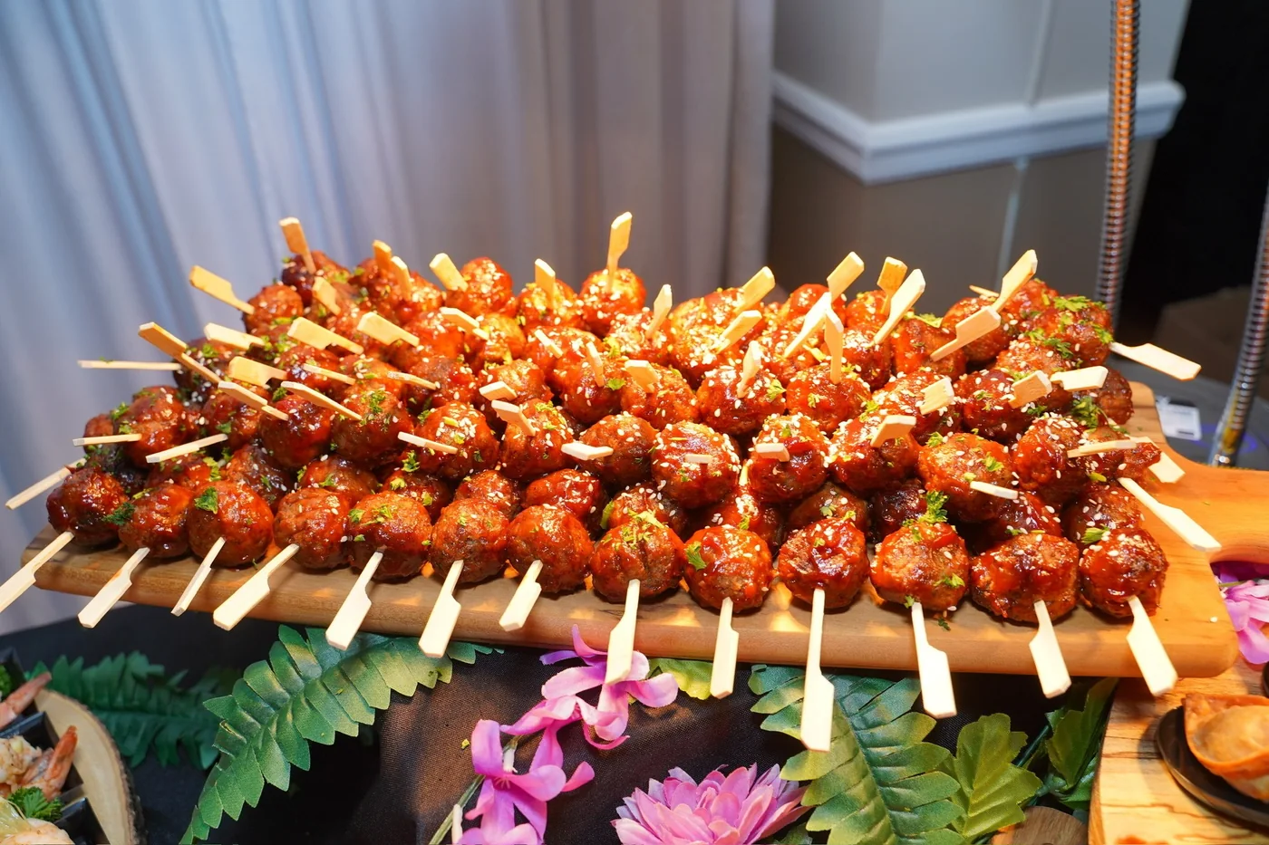 Glazed appetizer skewers arranged with tropical flowers